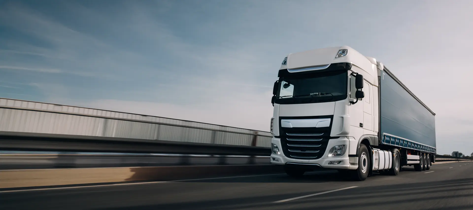 Weisser Sattelschlepper in Fahrt, neutral, blauer Himmel und Autobahnbruecke